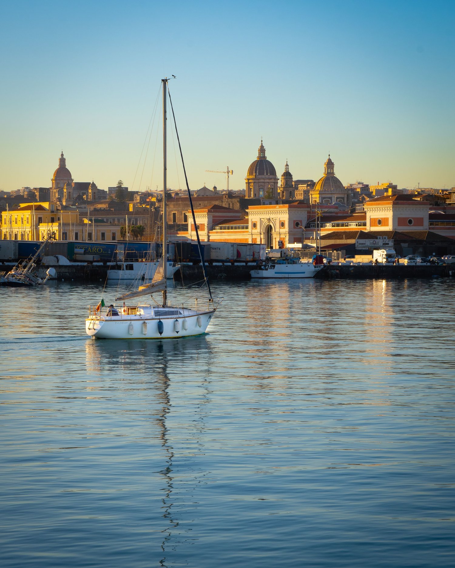 Sailing boat in Catania harbour at sunset, Mediterranean maritime photography.