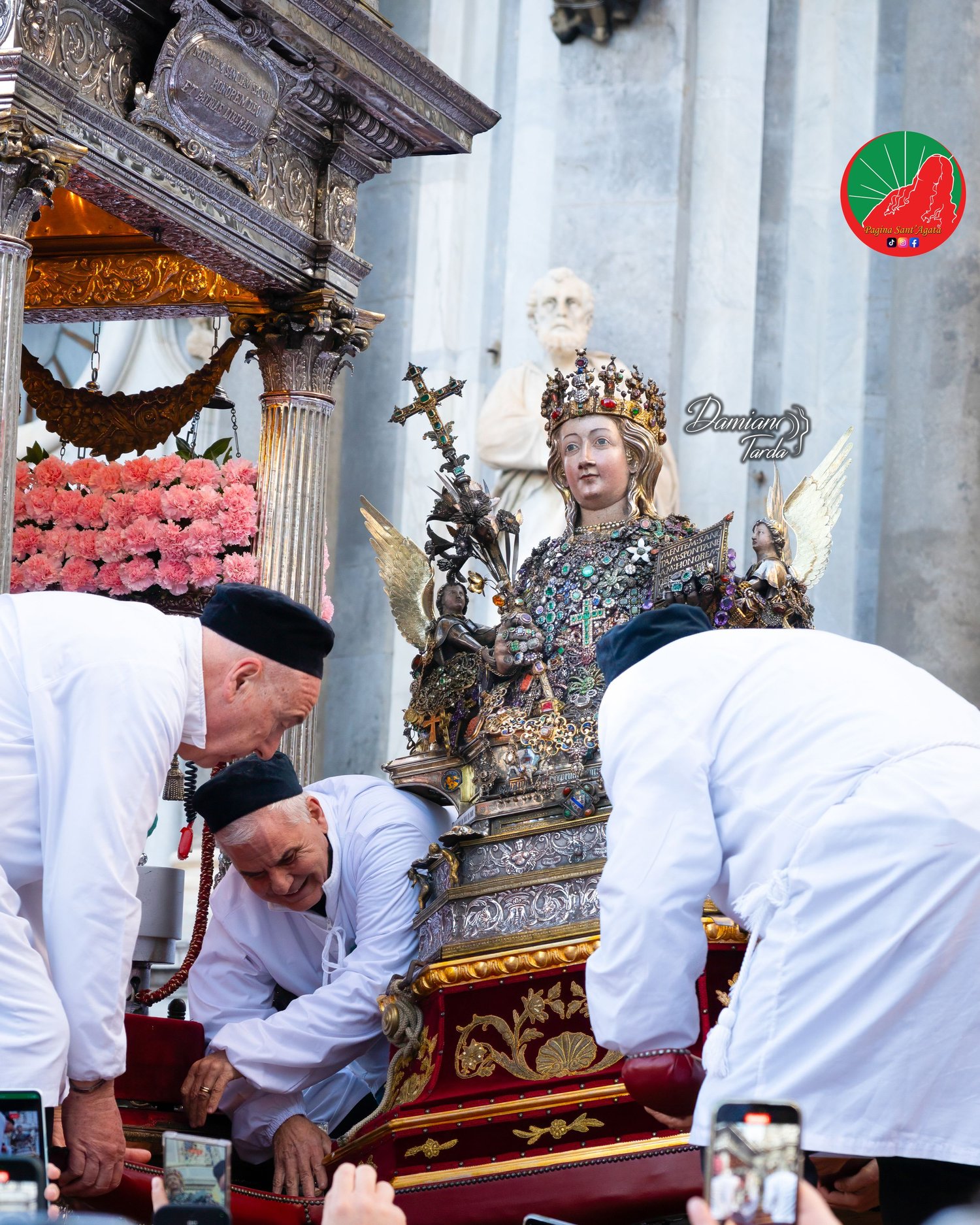 Devotees in white robes settle the bust of Saint Agatha on the fercolo.