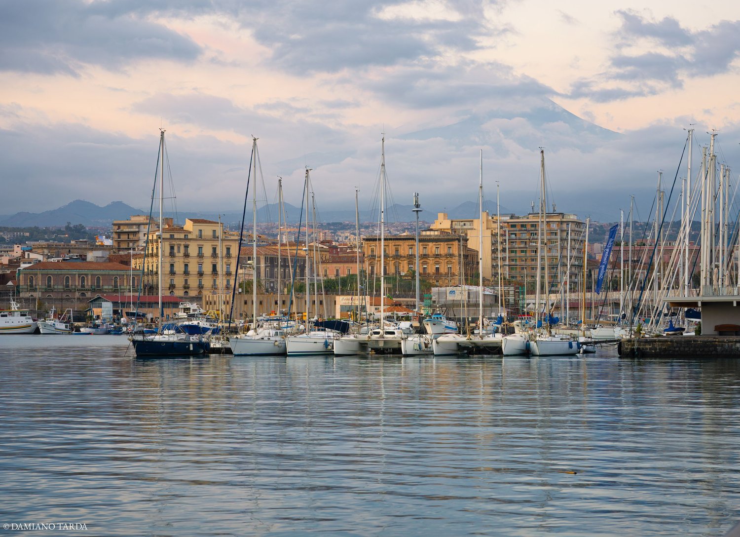 Landscape photograph of Catania seen from the harbour, the sea in the foreground and Etna in the background