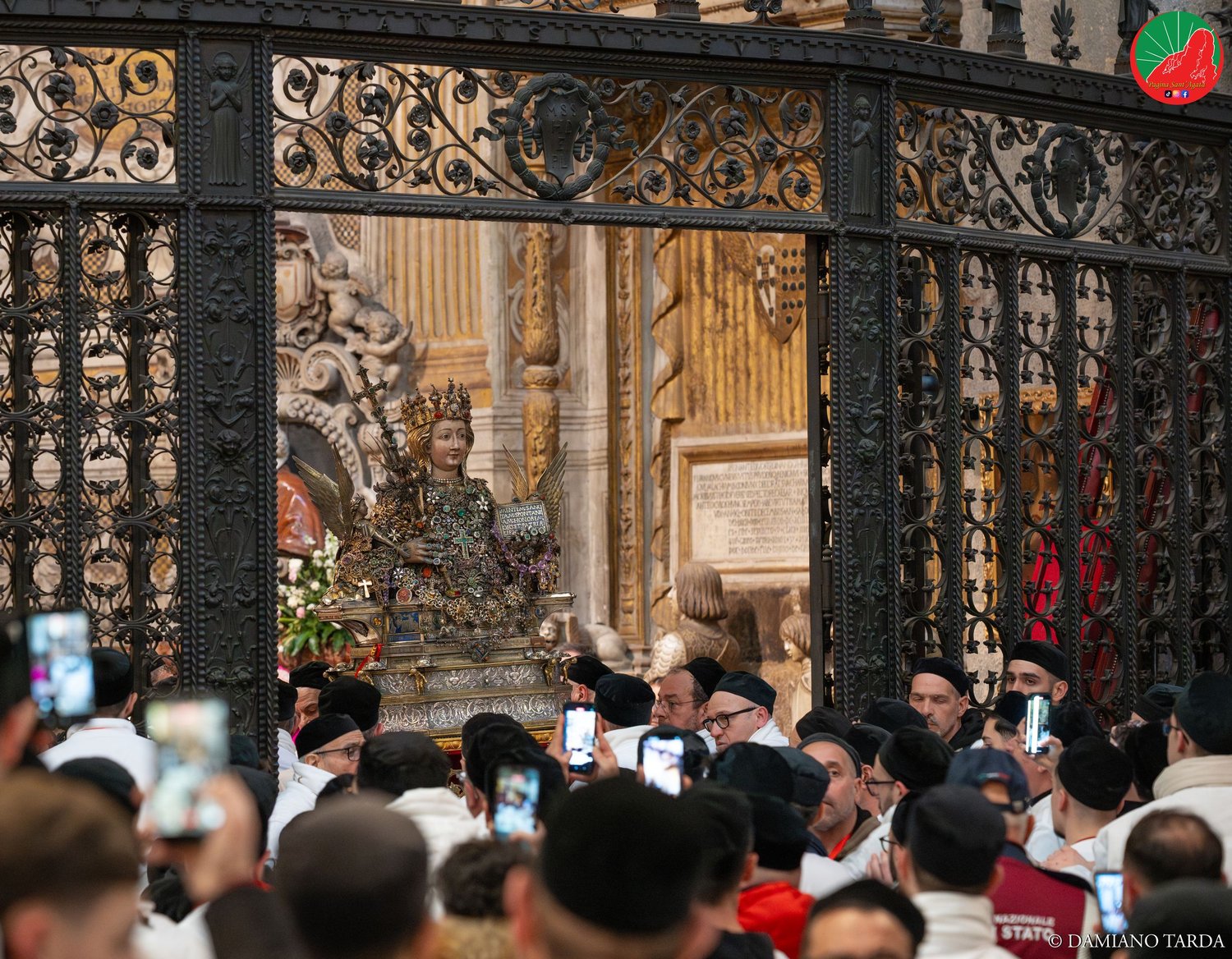 The faithful photograph the bust of Saint Agatha beyond the gate of her chapel in the Cathedral.