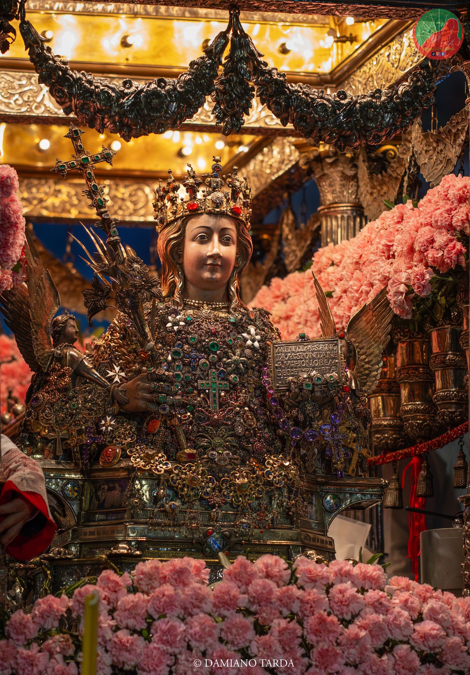 The bust of Saint Agatha on the fercolo among pink carnations and gilded decorations.