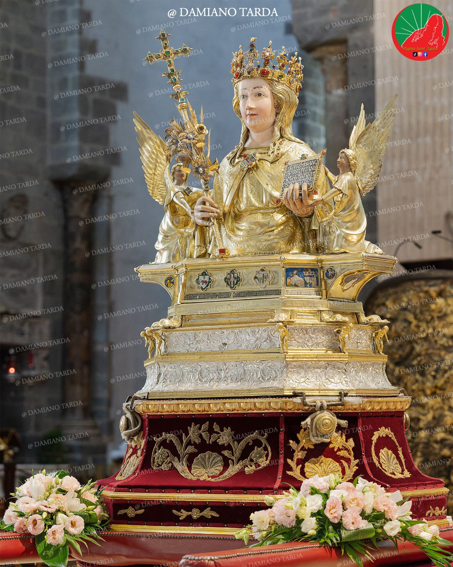 The reliquary bust of Saint Agatha after the restoration, without jewels and ex-votos, among white flowers.