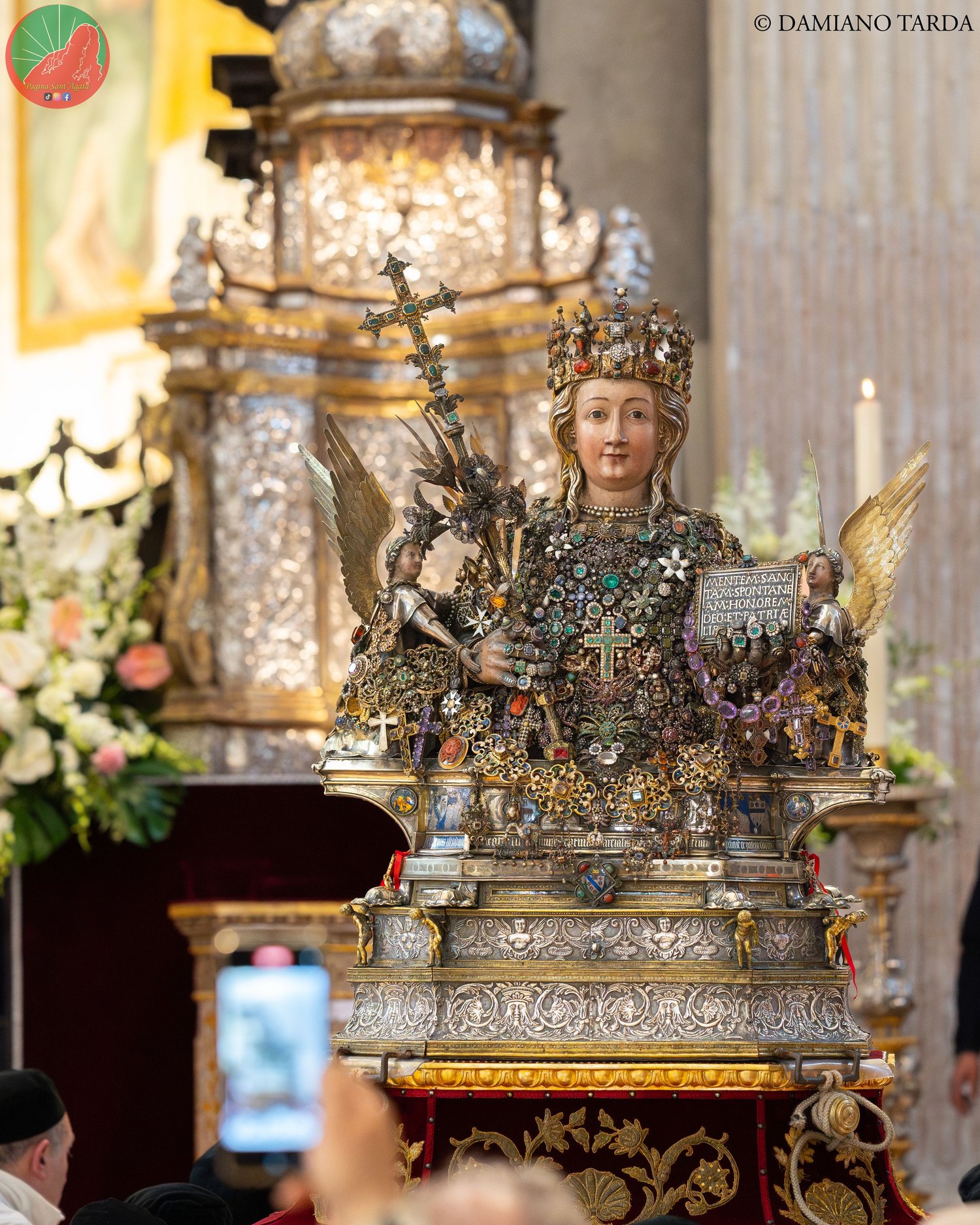 The reliquary bust of Saint Agatha in the Cathedral among flowers and the faithful, February feast.