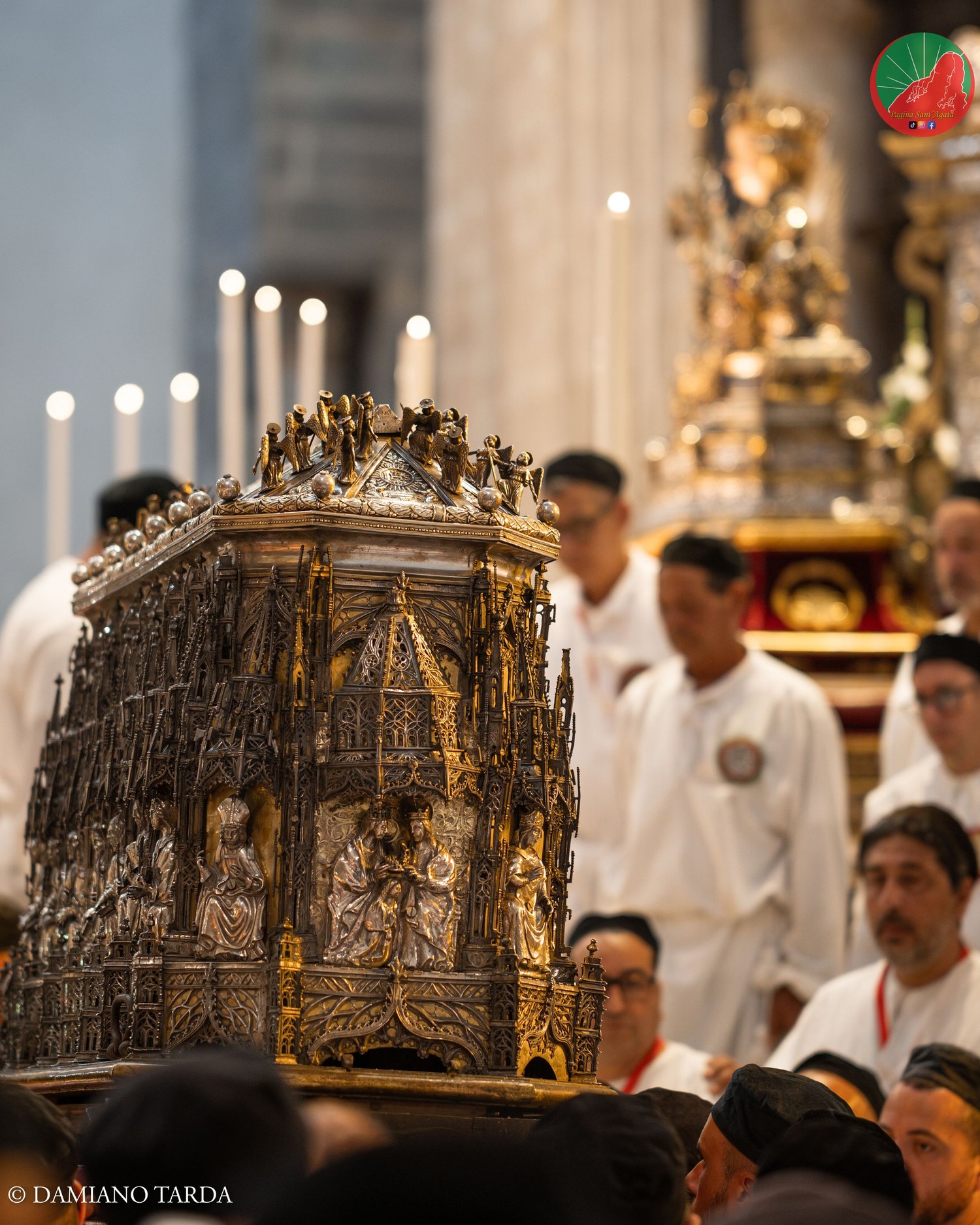 The casket with the relics of Saint Agatha carried by devotees in white robes in the Cathedral.