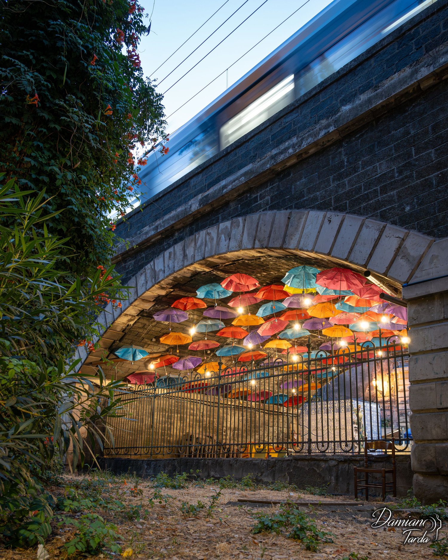 Coloured umbrellas under the arches of the Marina as a train passes, creative urban photography.