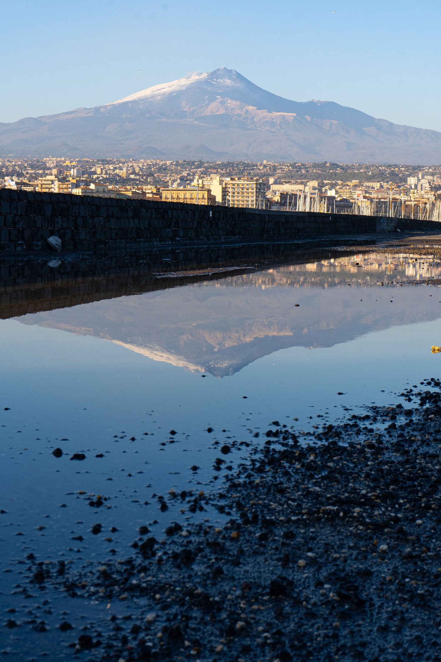 Etna reflected in the water of Catania harbour, contemplative landscape photography.