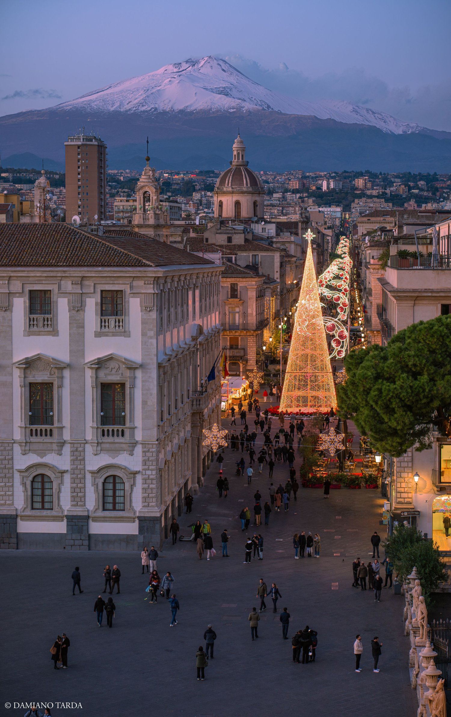 Via Etnea decorated for Christmas, with snow-capped Etna in the background